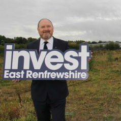Councillor Buchanan holding Invest sign